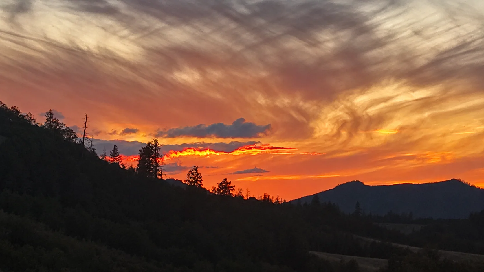Close view of orange sunset over a wooded ridgeline